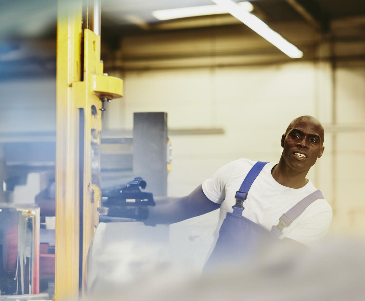 male looking away while operating a machine in a warehouse.
